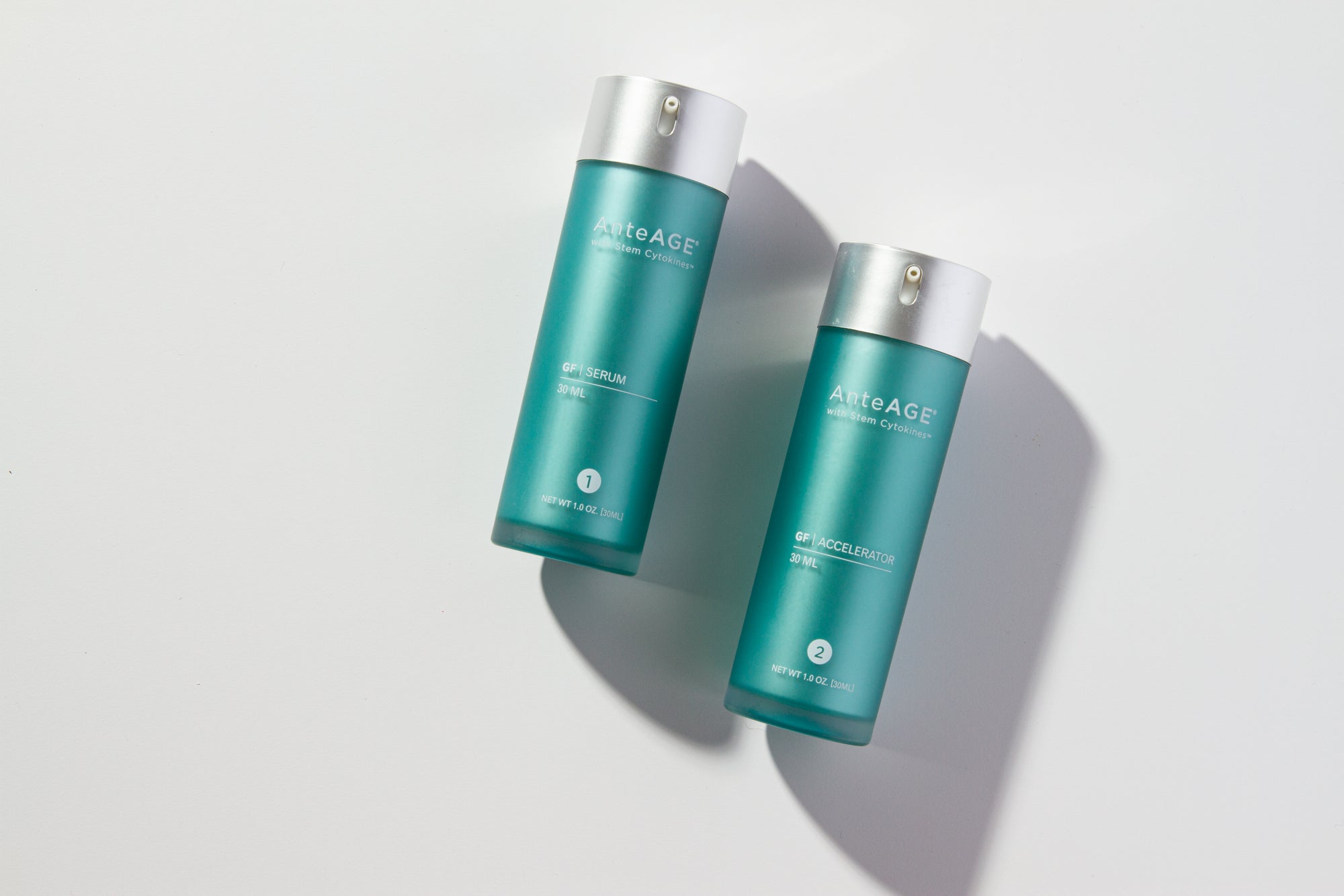 Two blue skincare bottles with white caps on a light gray background