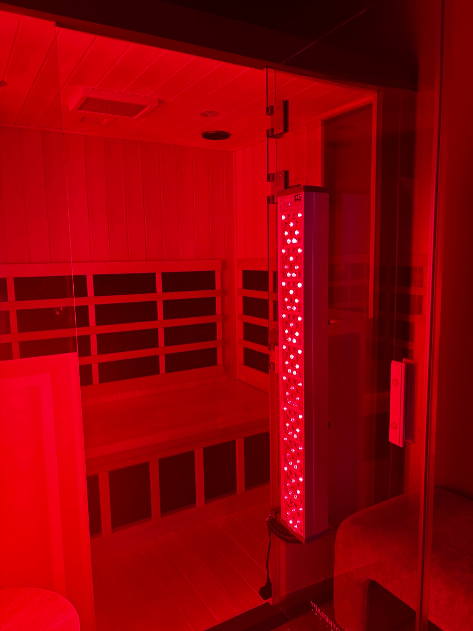Red-lit sauna with a vertical light fixture inside