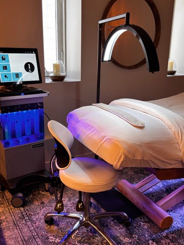 A hydrafacial machine beside a facial bed in a spa. 