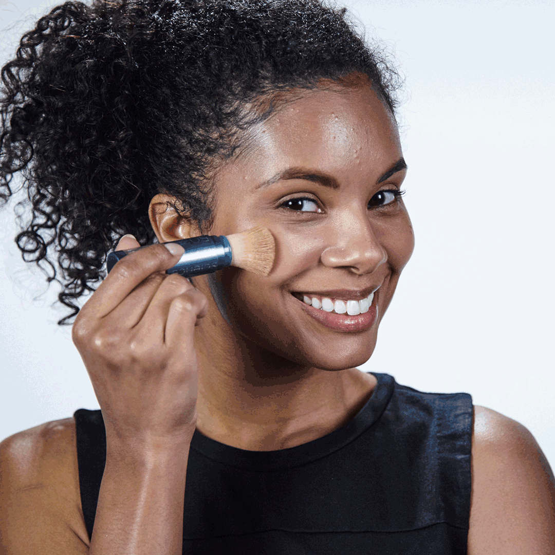 a woman applying colorescience brush on spf  to her cheeks