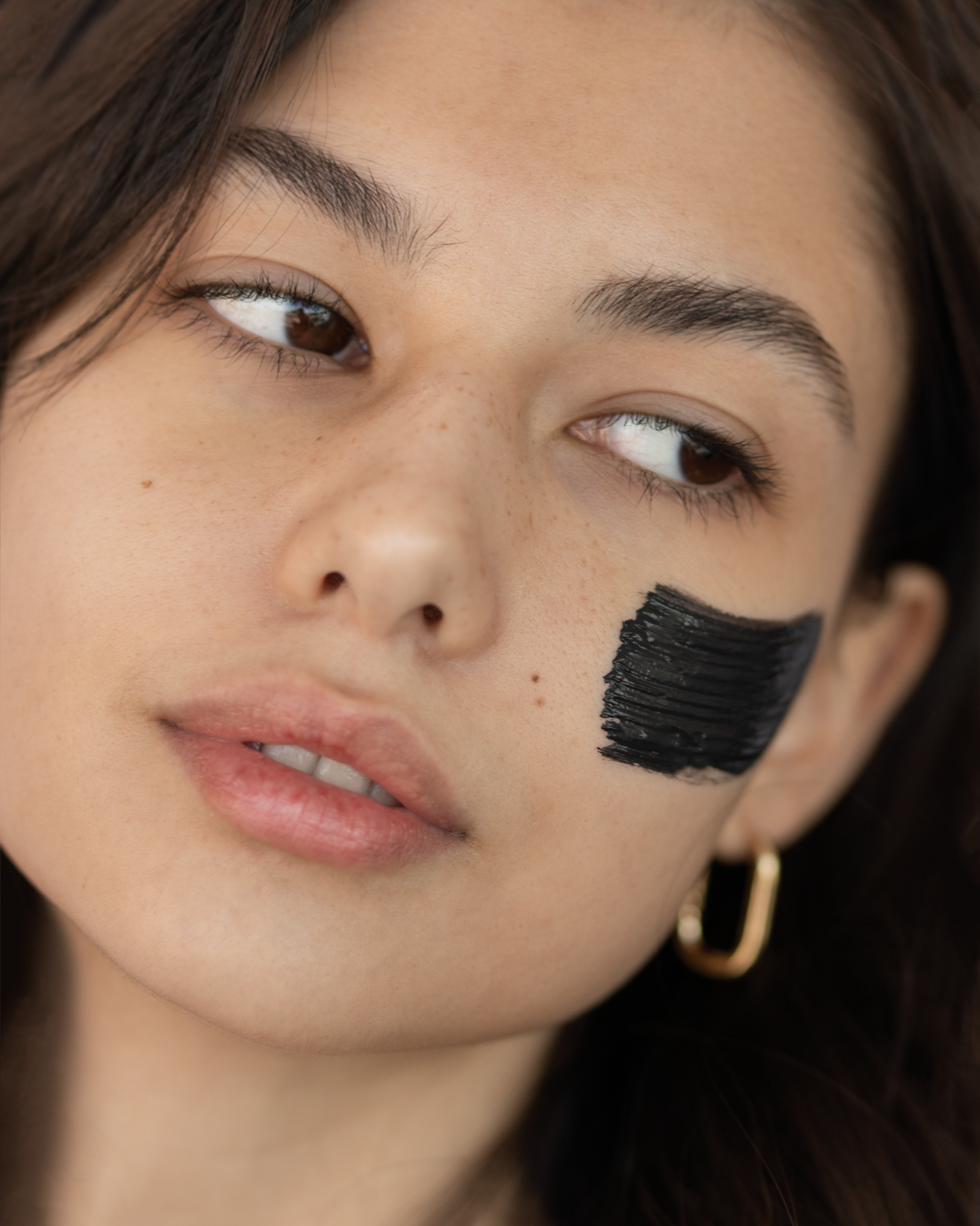 Green Envee Clear Complexion Mask on a womans cheek.
