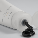 Tube of Green Envee Clear Complexion Mask  showing the black mask coming out of the bottle on a white background