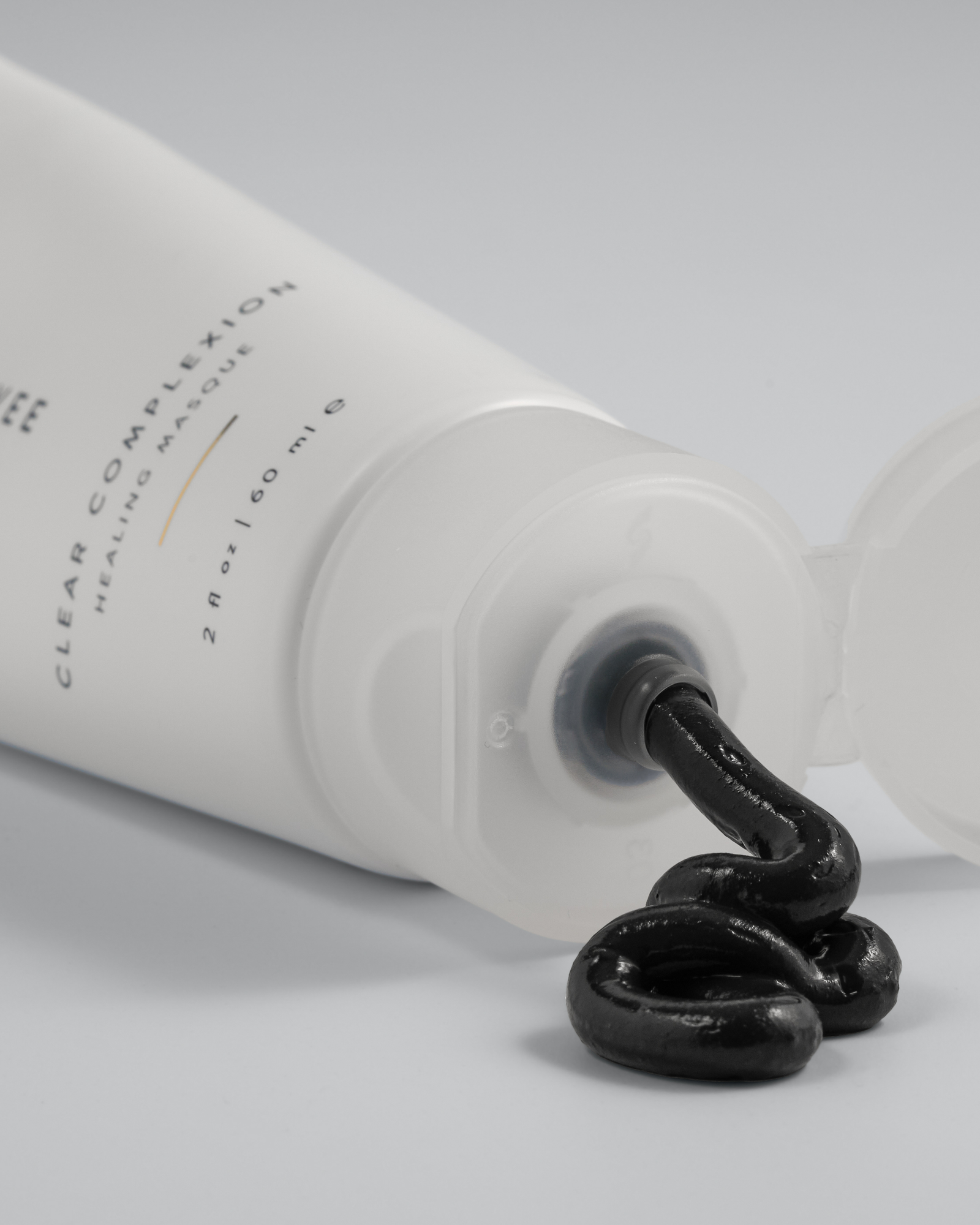 Tube of Green Envee Clear Complexion Mask  showing the black mask coming out of the bottle on a white background