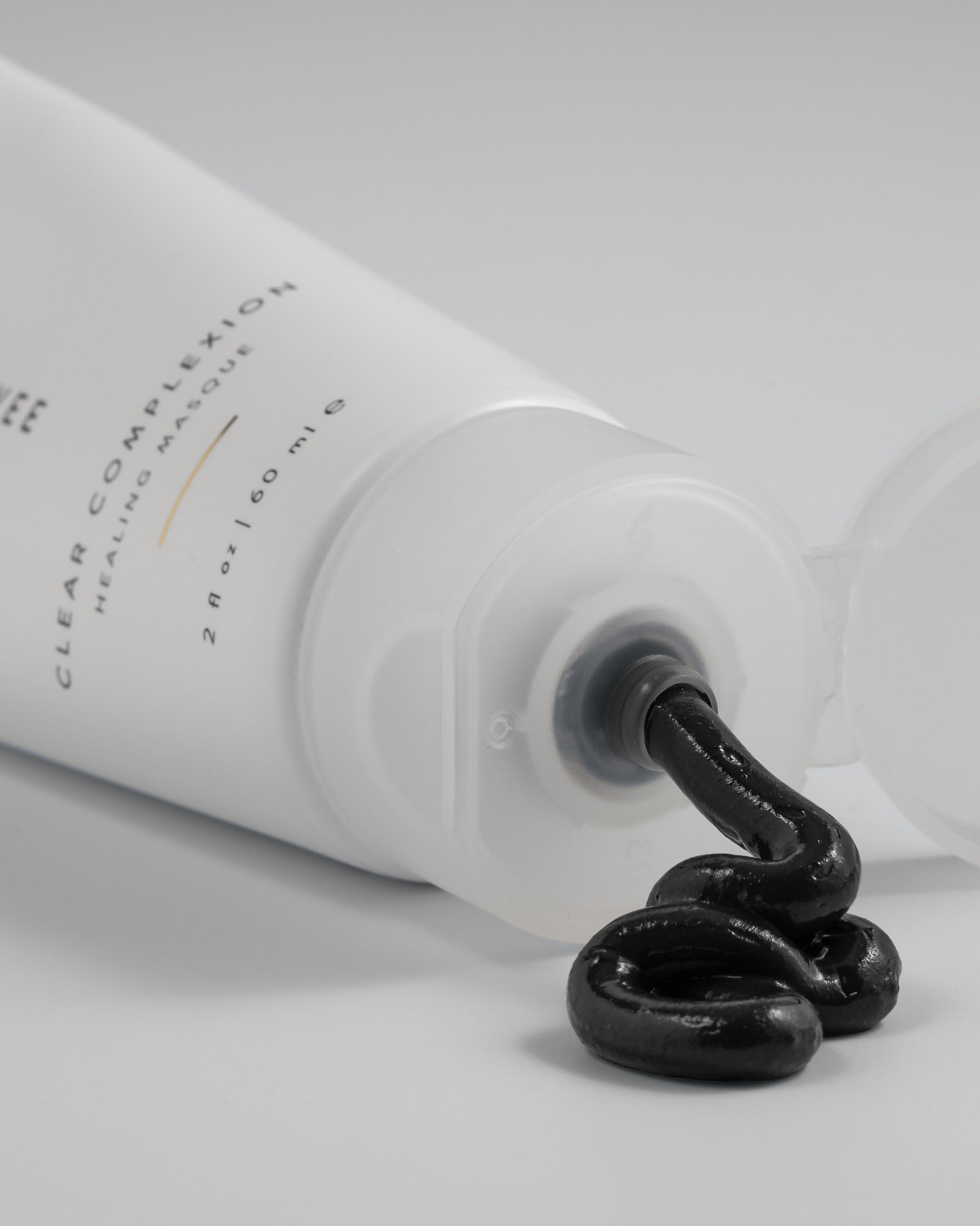 Tube of Green Envee Clear Complexion Mask  showing the black mask coming out of the bottle on a white background