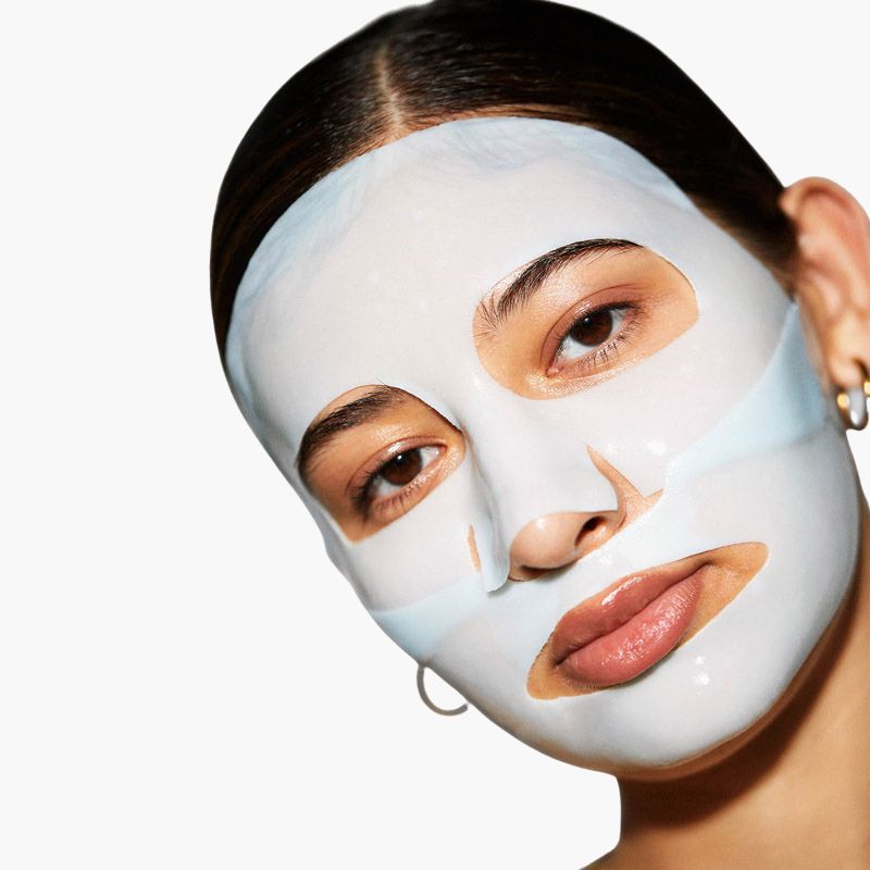 Woman wearing a white face mask on a plain background