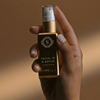 A hand holding a gold serum bottle 