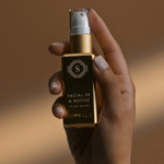 A hand holding a gold serum bottle 