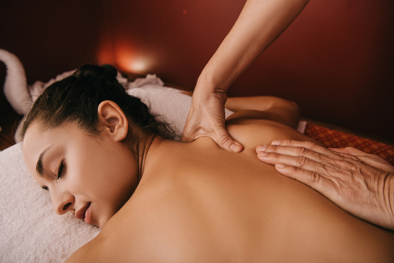 Person receiving a massage with a warm, reddish-brown background